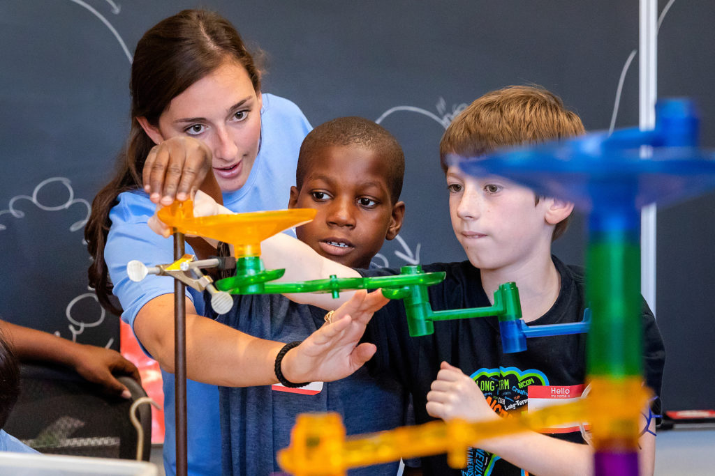 The UNC department of physics and astronomy hosted 4th-grade classes from three schools in the Chapel Hill-Carrboro City Schools district for Science is Awesome Outreach Day on May 15. UNC sophomore physics and math major Schuyler Moss helps students during a hands-on exercise at Phillips Hall. (photo by Johnny Andrews)