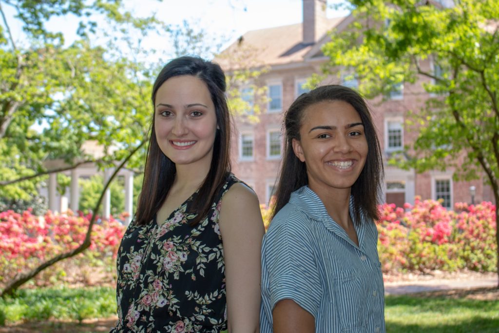 Hannah Herzog (left) and Morgan Vickers stand near the Old Well (in the background) on the Carolina campus.