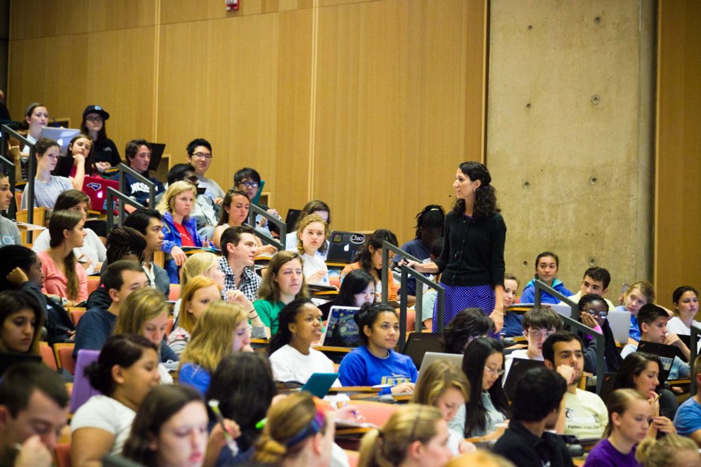 Kelly Hogan walks up and down the aisle in her large lecture class on biology, interacting with students. (photo by Vijy Sathy)