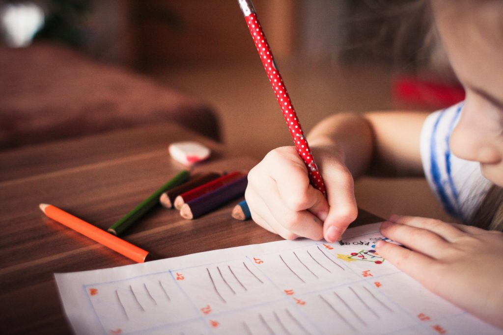 Closeup photo of child writing on a piece of paper.