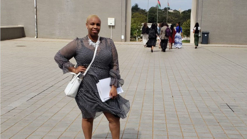 Randi Thompson stands on a large plaza in a black and white dress with her hand on her hip.