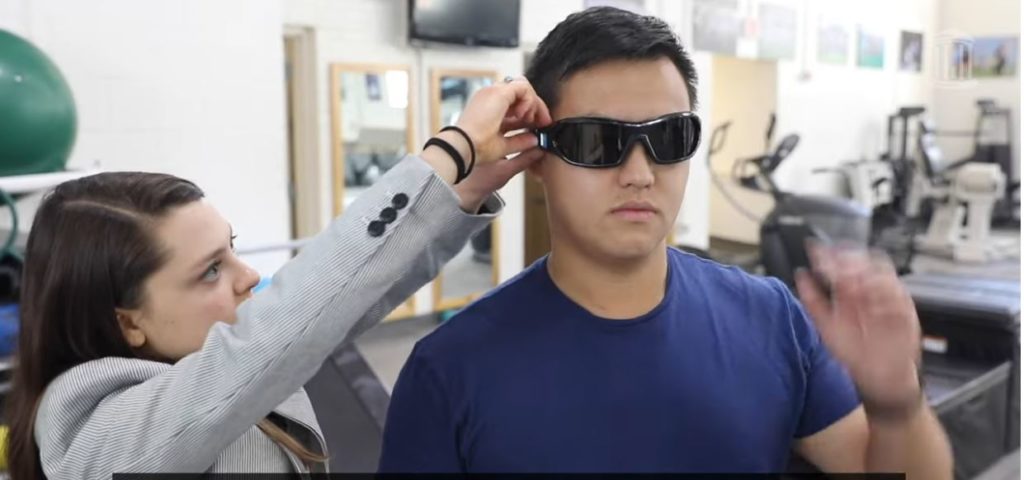 A researcher at the Gfeller Center places dark glasses on a study participant.