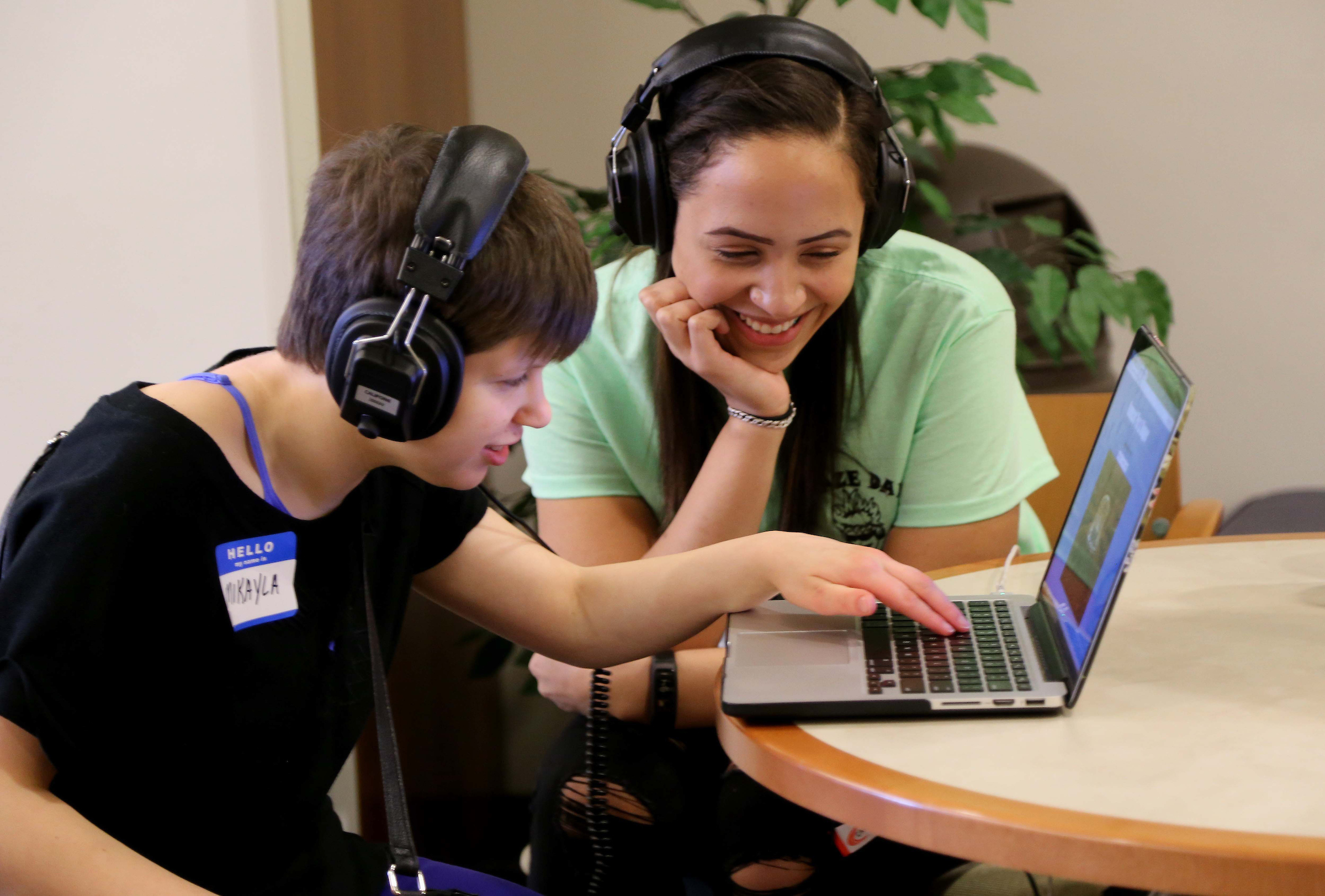 Maze Day invites K-12 students with visual impairments, along with their parents/guardians and teachers, to the computer science department to experience a wide variety of educational games and tools created just for them. (photo by Emilie Poplett) A young male student with headphones is sitting with an older female student and they are looking at something on a laptop computer.