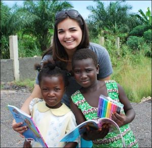 Leondis poses with two children who will benefit from Project Nyame Nsa.