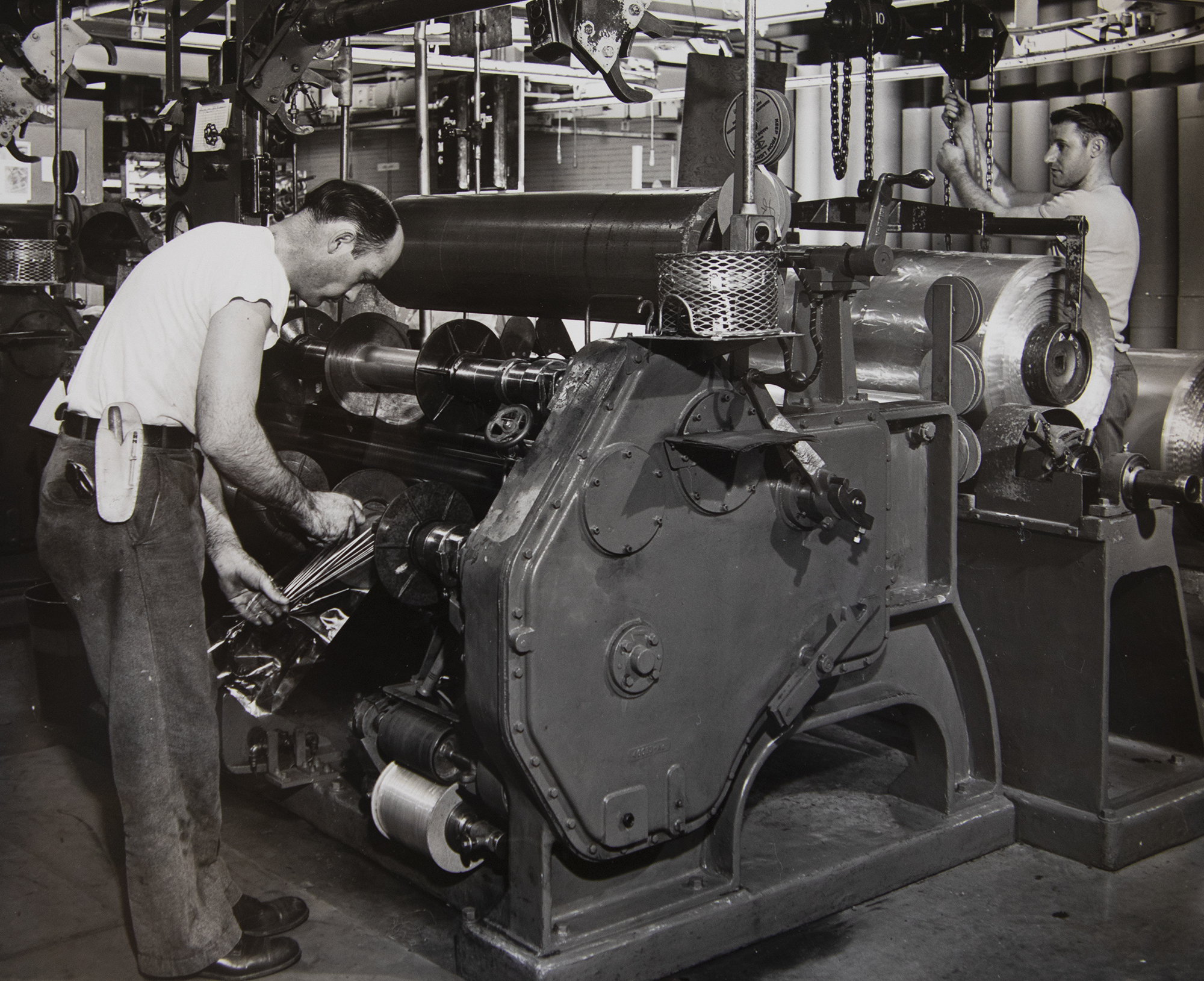 Workers in a DuPont Company plant thread a slitting machine, which cuts the wide cellophane sheet (seen on the right) into narrower strips for wrapping bread and other articles. (photo courtesy of University Archives)