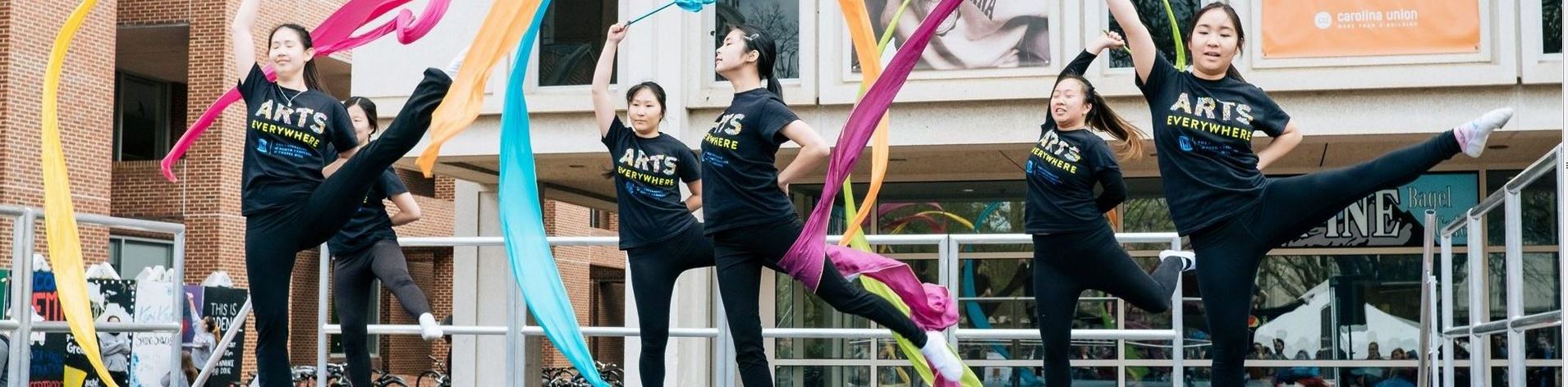 Dancers in T-shirts saying "Arts Eveywhere" dance in The Pit on campus.