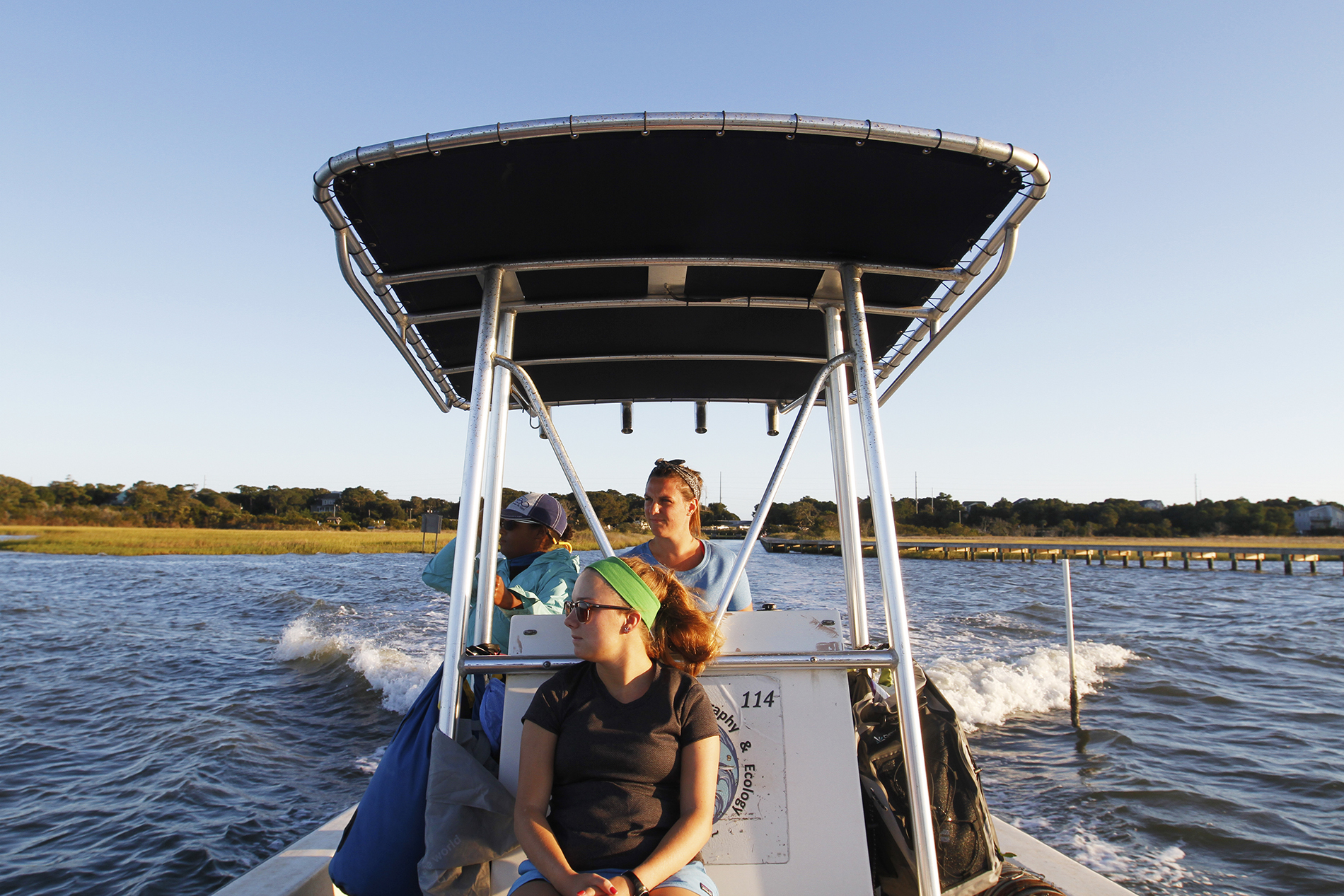 Shelby Ziegler and her team head out on a boat in the marshes to do their research, with the water from the wake of the boat flowing behind them.