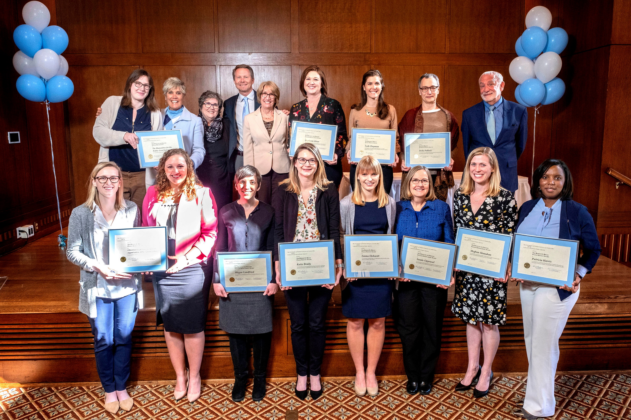 Photo shows two lines of public service award winners holding their award plaques.