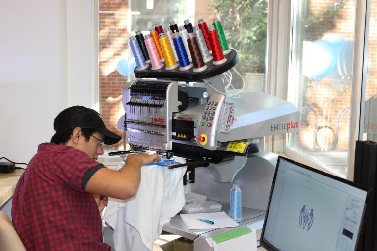 First-year student Gustavo Rios demonstrates the use of an embroidery machine.