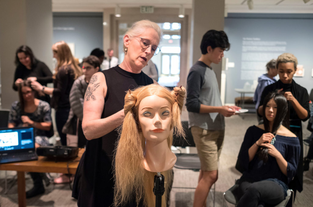 Janet Stephens shows participants in her workshop at the Ackland how the elaborate braided hairdos of ancient Roman women were secured with needle and thread. (photo by Jon Gardiner)