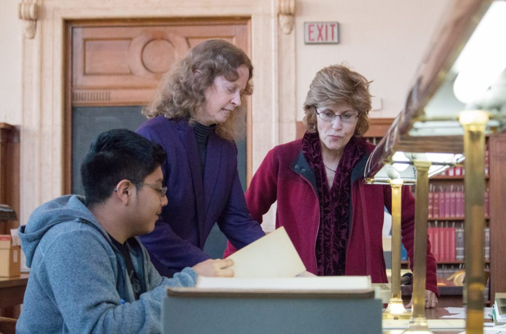 Professors Gabrielle Vail (left) and Patricia McAnany) work with a student in Wilson Library on research for the Maya from the Margins project. (photo by Kristen Chavez)