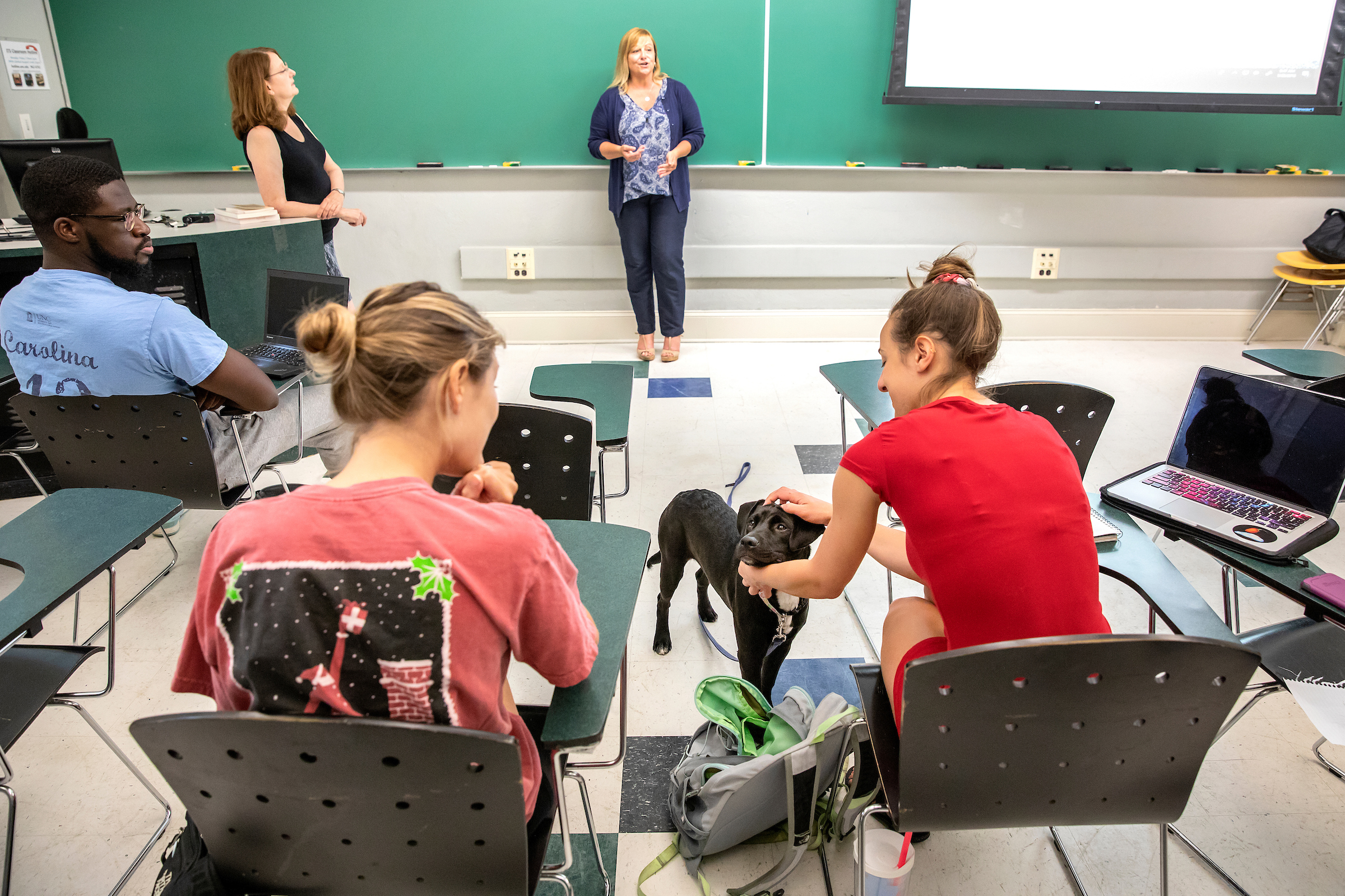Sunny Westerman from UNC PAWS talks with the class, while support dog Posey visits with students. Anthropology associate professor Margaret Wiener, at left, looks on. (photo by Johnny Andrews)