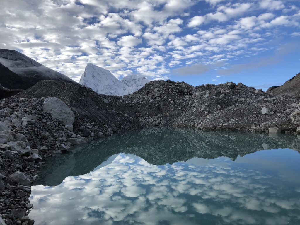 Early morning clouds are reflected in a blue pool on the Ngozumba glacier in the Gokyo Valley of Nepal, with the twin peaks of Cholatse and Arakam Tse visible in the background. (Photo by Roberto Camassa.)