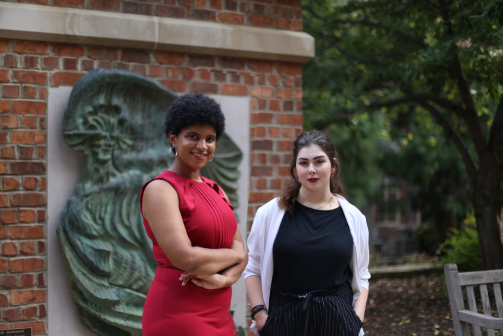 From left, Grace Morse and Savannah Bradley are the 2018 Thomas Wolfe Scholars. (photo by Sarah Boyd). They are standing in front of the Thomas Wolfe Memorial on campus.