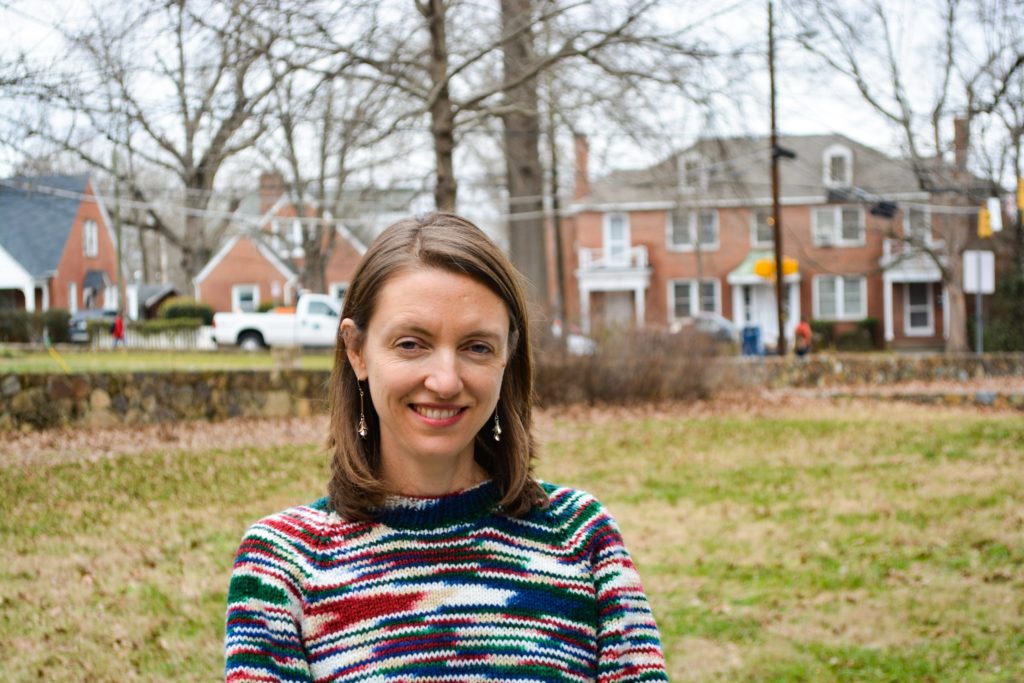 Hannah Gill is the director of the Latino Migration Project at UNC-Chapel Hill. She is pictured on the lawn with buildings in the background.