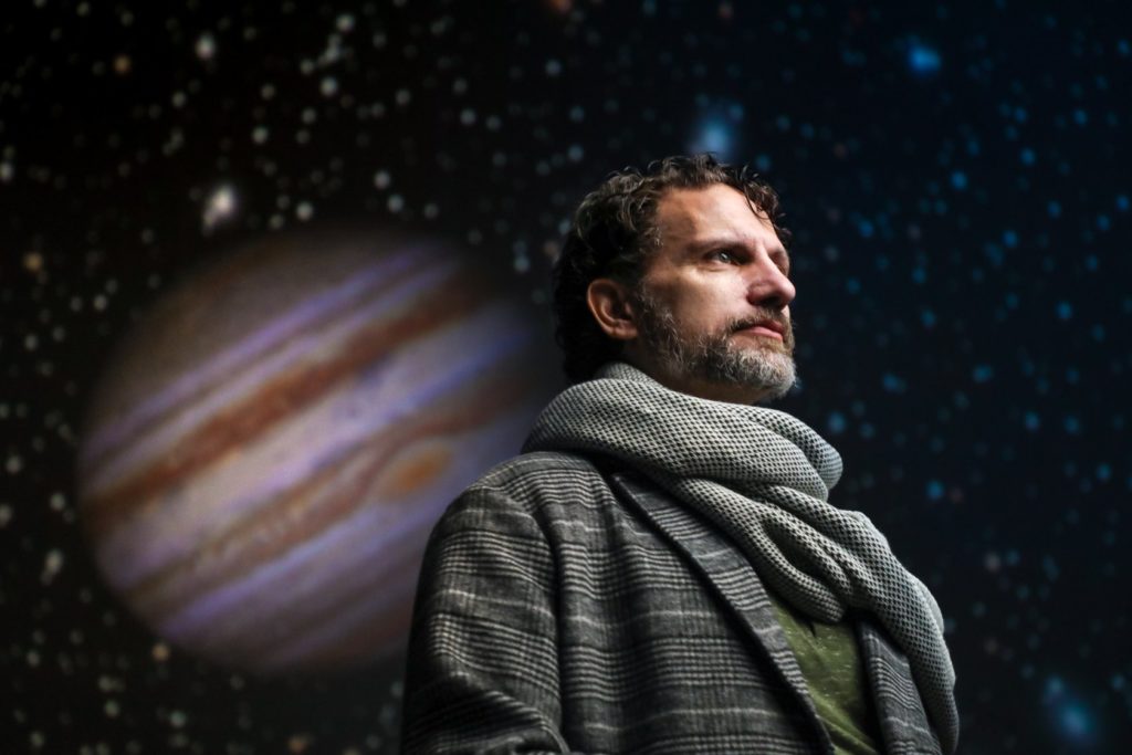 Ron Menzel as Galileo in the Morehead Planetarium dome, as an image of Jupiter looms behind him.