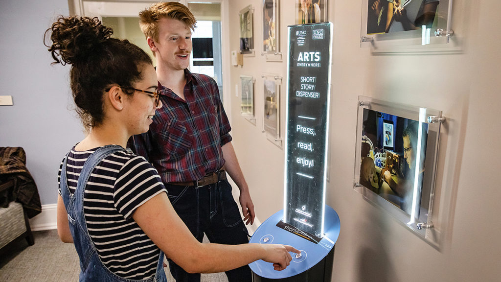 Seniors Elina Rodriguez and Hampton Smith use a vending machine that dispenses short stories on April 5 in South Building. (Johnny Andrews/UNC-Chapel Hill)