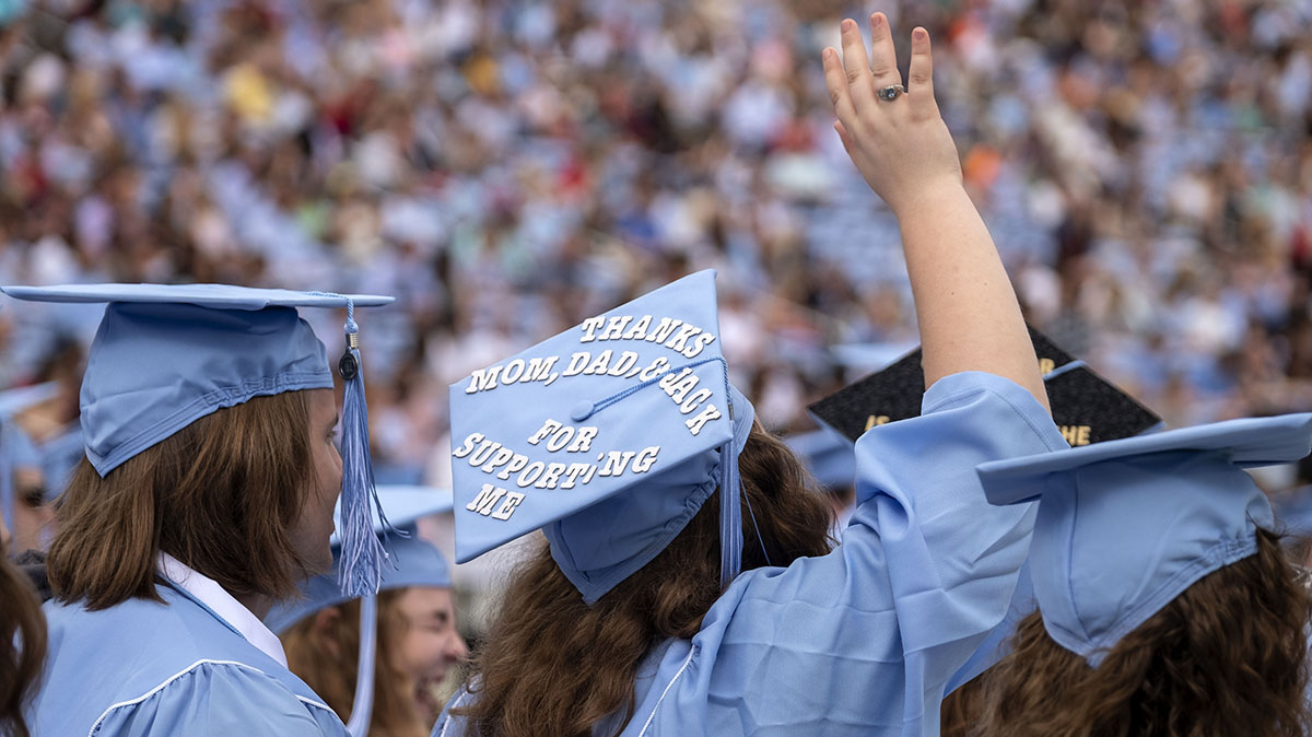 A closeup of a student's hat at commencement reads: "Thanks, Mom, Dad and Jack for Supporting Me."