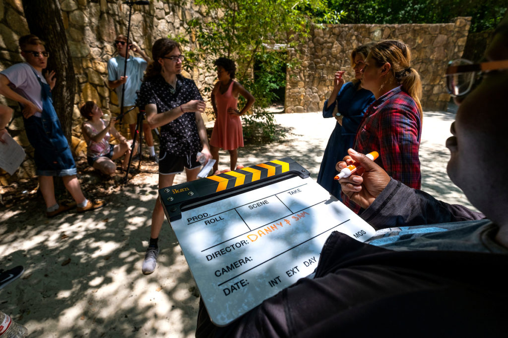 Prior to filming a scene for “Though Time May Change,” student director Dan Ferguson talks with student actors Julia Thompson and Madison Schultz while Anane Ward notes details for the take on a slate. (Jon Gardiner/UNC-Chapel Hill)
