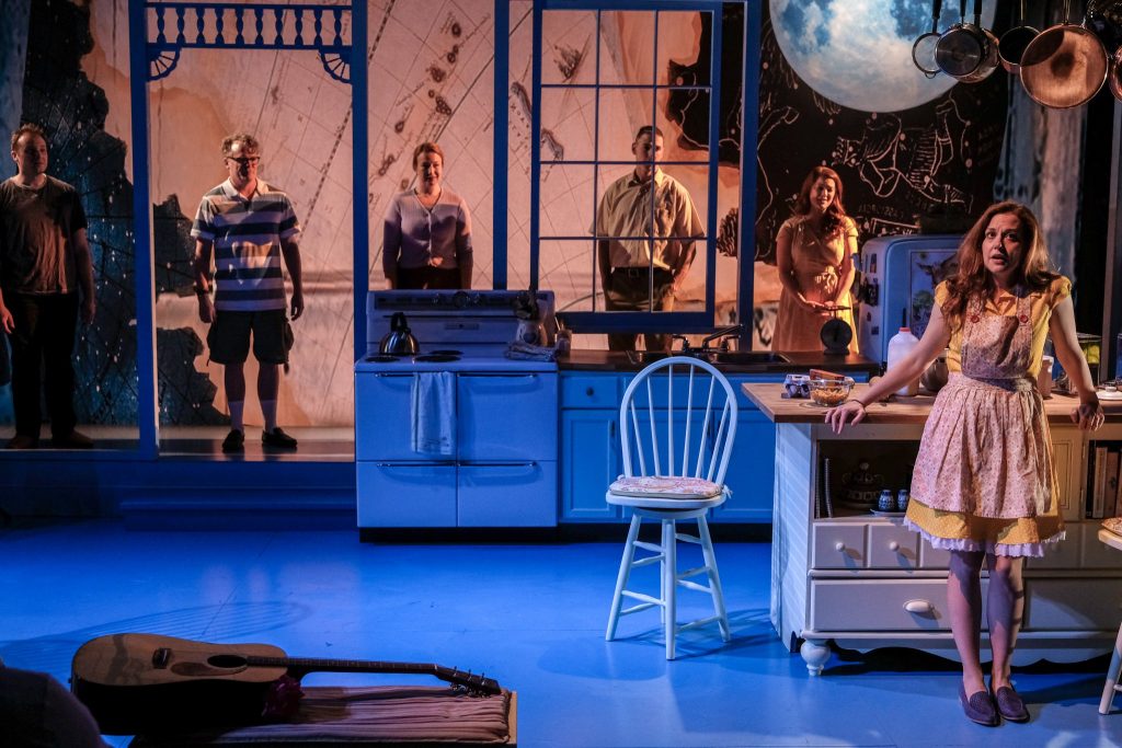 "Birthday Candles" is headed for Broadway. Photo shows a woman on stage in a kitchen and men in the background of the photo. Photo is from a previous stage production of the play.