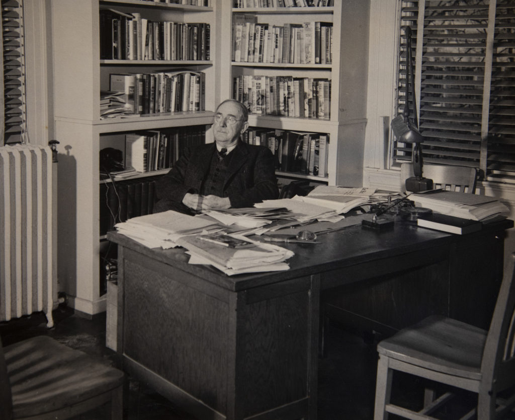 Howard Odum sits in his "famous" office in the UNC Alumni Building. Much like his home office, it was covered in books and papers that he didn't allow anyone to reorganize. (photo courtesy of University Archives)