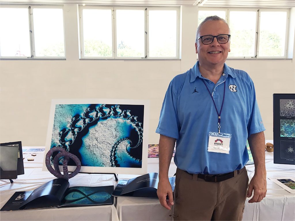 Mark McCombs (top) exhibits his art at the Bridges 2018 Conference in Stockholm, Sweden. The origami sculpture in the forefront is “The answer inside” and the fractal image in the background is “Myth of Sisyphus.” This origami sculpture (below) is called “And yet you go on.”