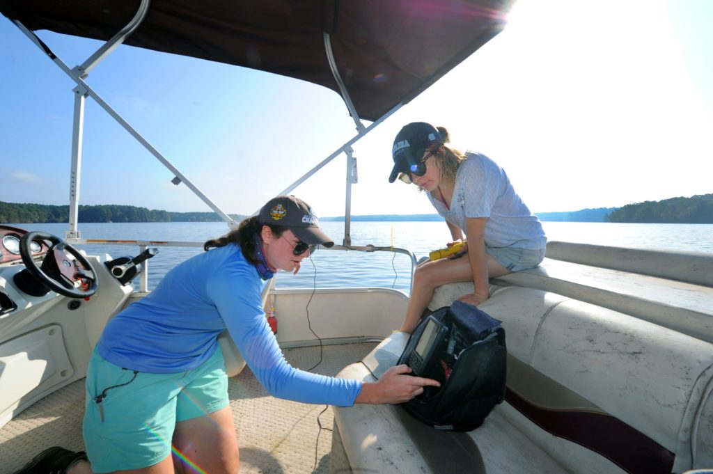 aylyn Gootman works with a student to take water quality measurements on a boat on Jordan Lake.metry-and-water-quality-measurement