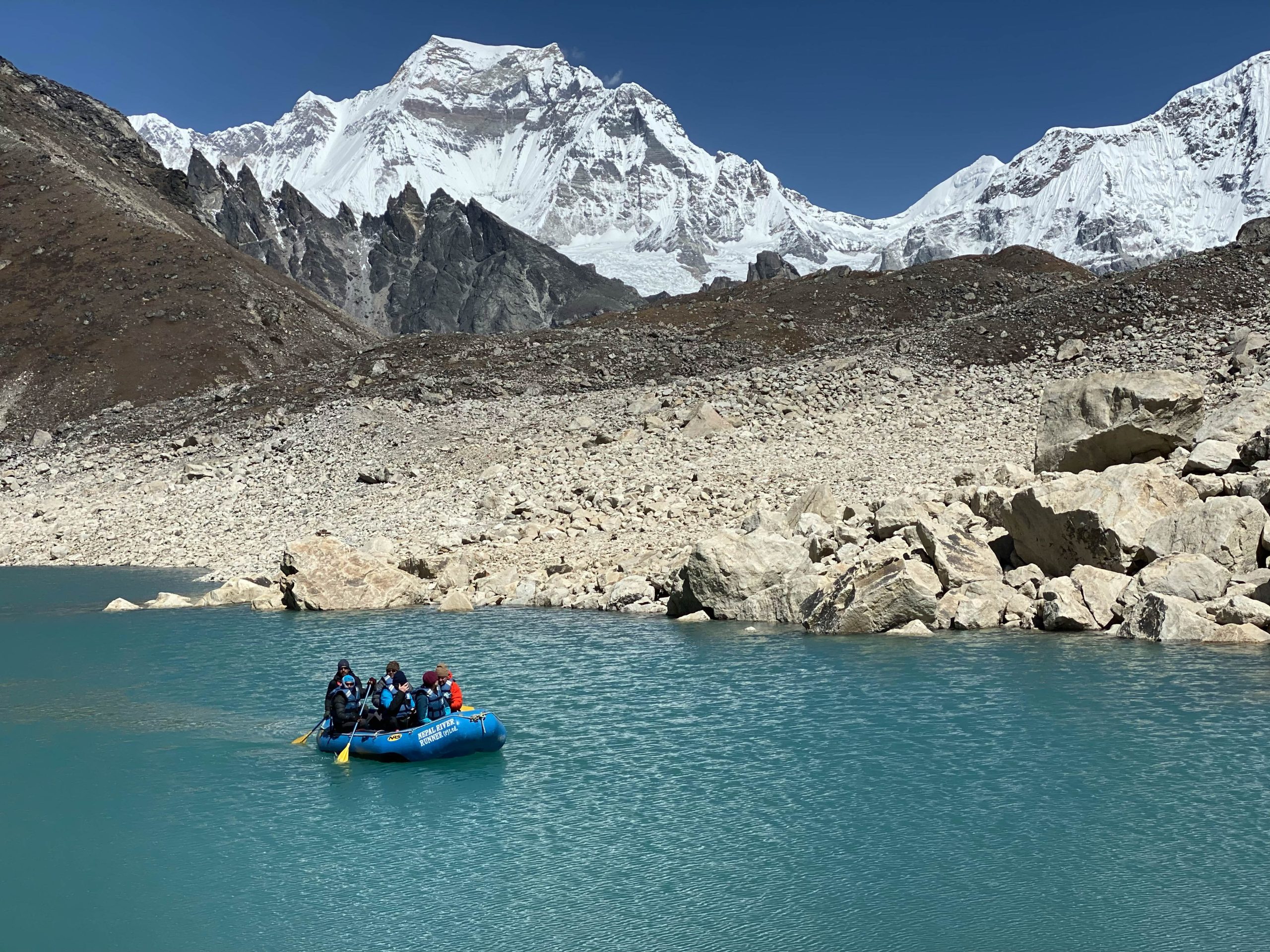 The researchers working on lake 5, a new lake they explored during the return trip. (photo by Roberto Camassa). Photo shows them on a raft in the middle of the beautiful blue lake.
